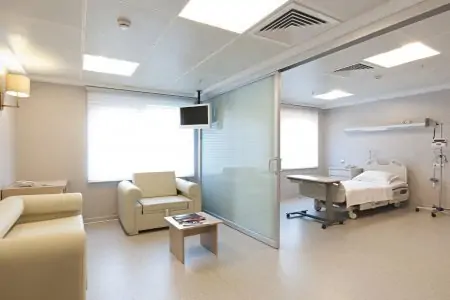 غرفة مرضى في عيادة Vita Estetic بسرير مستشفى ومنطقة انتظار للزوار