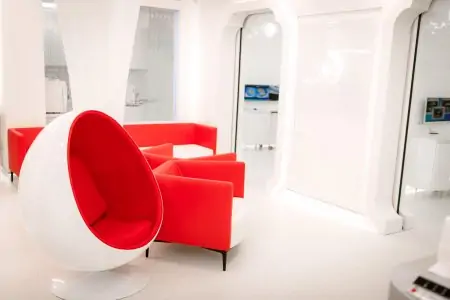 منطقة انتظار حديثة في عيادة MistoDent بكراسي حمراء وديكور أبيض