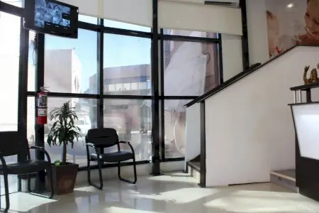 Área de espera en Dental Brush Clinic con asientos modernos y grandes ventanales