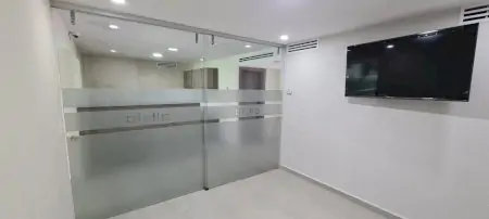 منطقة انتظار حديثة في Alivia Clinica Monterrey بأبواب زجاجية وتلفزيون