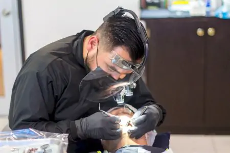 Dentista realizando procedimiento dental en Dental Brush Clinic con equipo avanzado