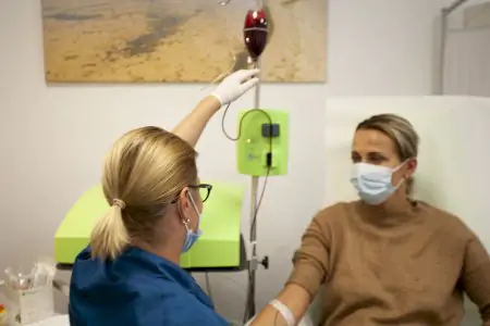 ممرضة تعطي علاج وريدي لمريضة في غرفة علاج عيادة Pallas