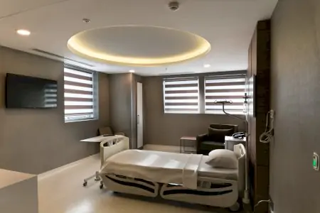Habitación de paciente en IC ESTHETIC Clinic con cama moderna y comodidades