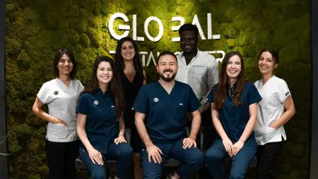 فريق طب الأسنان في مركز Global Dental Center، عيادة حديثة أمام جدار أخضر