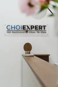 Mostrador de recepción en CHOIEXPERT Hair Transplant Clinic con cartel en la pared