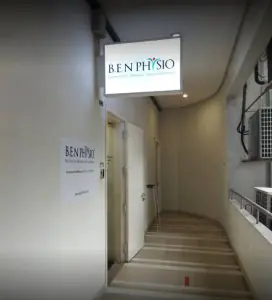 Pasillo de entrada de la clínica Benphysio con letrero y puerta abierta