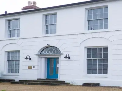 Fachada de la clínica UK SKIN con paredes blancas y puerta azul