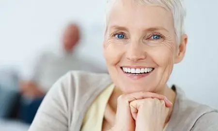 سيدة مسنة تبتسم وتعرض نتيجة زراعة الأسنان في Will Murphy Dentistry