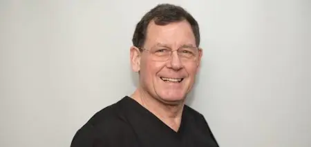 طبيب أسنان بالزي الرسمي في عيادة Hawkins Dental & Implant Clinic
