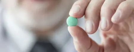 Médico sostiene pastilla verde para tratamiento médico