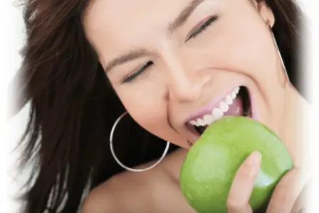 امرأة بأسنان صحية تقضم تفاحة خضراء، Thantakit Dental Center بانكوك