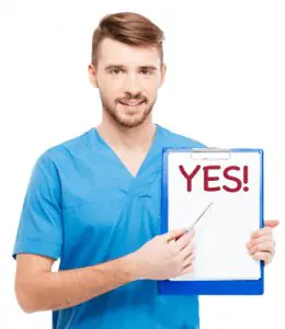 Personal de Family Dental Clinic PC con uniforme azul sostiene portapapeles con YES