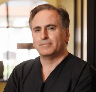 جراح تجميل في عيادة Jaibaji Plastic Surgery يرتدي زيًا مهنيًا