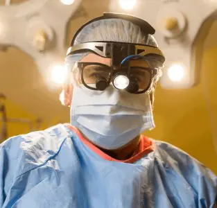 جراح في غرفة العمليات في Jaibaji Plastic Surgery يرتدي نظارات جراحية وقناع