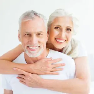 Pareja mayor sonriendo con dientes sanos tras tratamiento dental en Dental Pearls