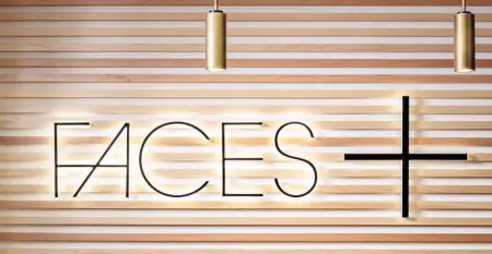 شعار عيادة Faces Plus على جدار خشبي حديث في Plastic Surgery San Diego