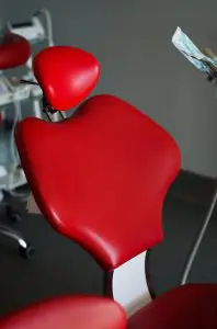 كرسي أسنان في مركز Albusdent لطب الأسنان مع تنجيد أحمر حديث