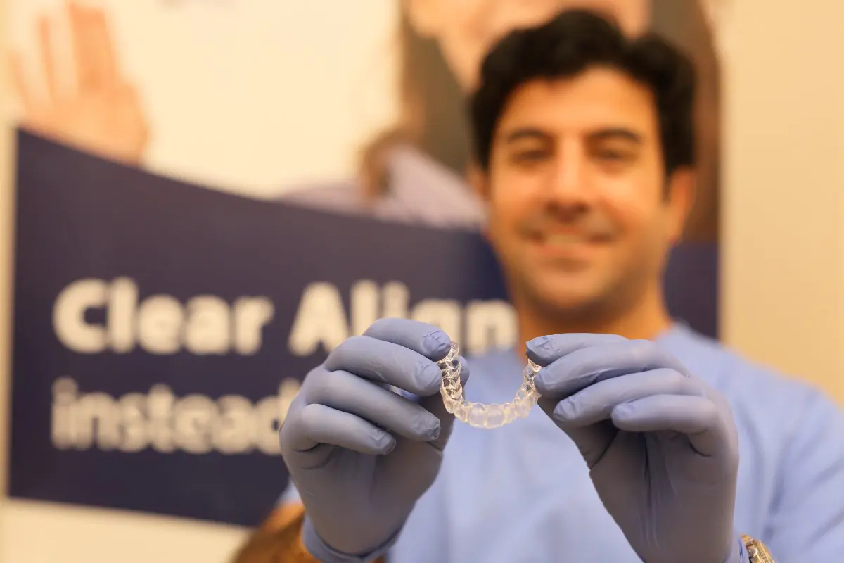 Dentiste au Dentium Implant Center tenant un aligneur transparent pour orthodontie