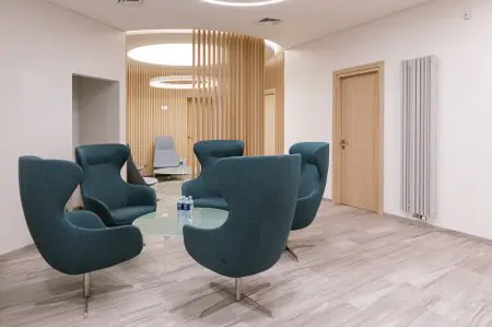 منطقة انتظار حديثة في MaxxClinic بكراسي زرقاء وطاولة زجاجية