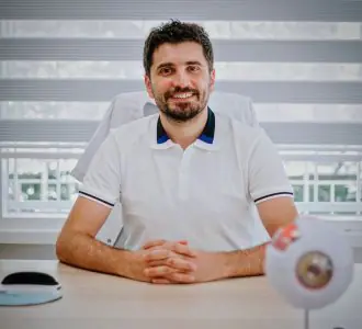 طبيب عيون في مكتب استشارات EyeWell Clinics مع نموذج عين على المكتب