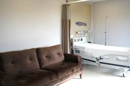 Habitación de paciente en Medivia Hospital con cama hospitalaria y sofá marrón