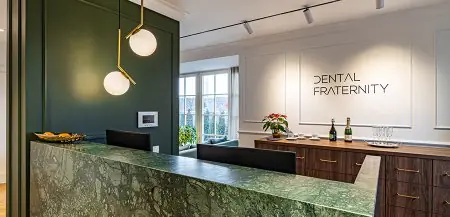 Área de recepción en la clínica Dental Fraternity con mostrador de mármol verde moderno