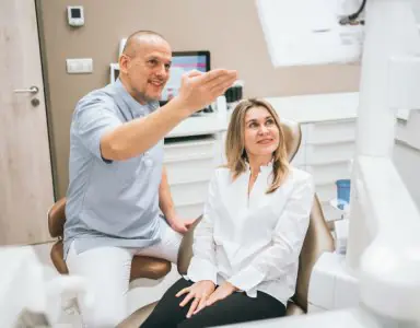 طبيب أسنان يستشير مريضًا في غرفة علاج حديثة في Schill Dental Clinic Prague