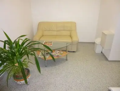 Sala de espera en PERLAN DENTAL CLINIC con sofá, revistas y planta de interior