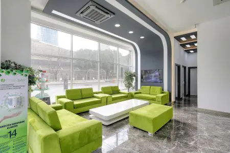 منطقة انتظار في عيادة Clinichair بأرائك خضراء حديثة ونوافذ كبيرة