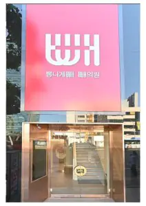 Entrada exterior de Bbae Clinic con cartel rosa en Seúl, Corea del Sur