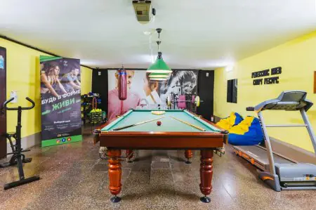 Sala de recreación y fitness en la clínica Renaissance-Kyiv con billar y equipos de gimnasio