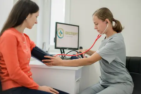 طبيب يقيس ضغط الدم في غرفة الاستشارة في Expert Clinic