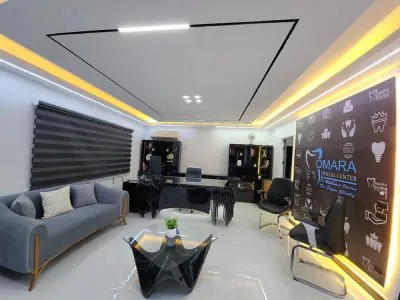 منطقة استقبال حديثة في مركز Omara Dental Center بأثاث أنيق وشعار طب الأسنان