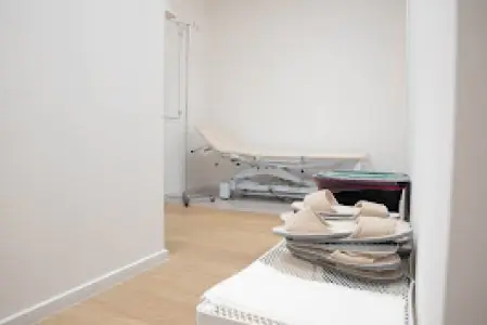 غرفة فحص المرضى في عيادة Dr. GASTRO بسرير طبي ونعال