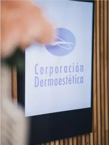 Cartel digital con el logo de Corporación Dermoestética en la entrada de la clínica
