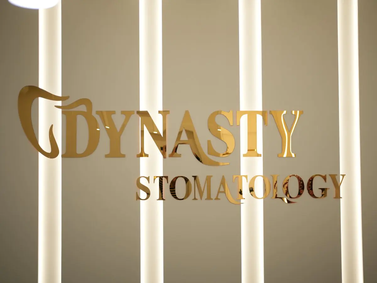 شعار عيادة Dynasty Stomatology على جدار مضاء في مركز طب الأسنان في كراكوف