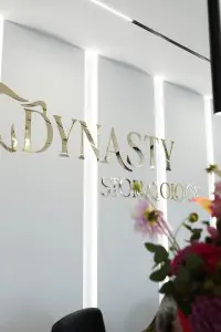 جدار استقبال حديث مع شعار عيادة Dynasty Stomatology في براغ وزهور