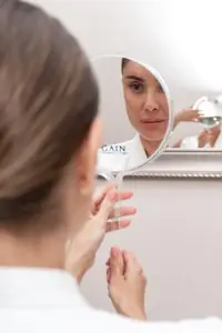 مريض يفحص وجهه في المرآة في عيادة PERFECT SKIN CANCÚN للأمراض الجلدية