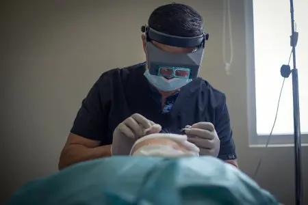 إجراء زراعة الشعر في عيادة Cancun Hair Restoration، جراح يستخدم عدسات مكبرة