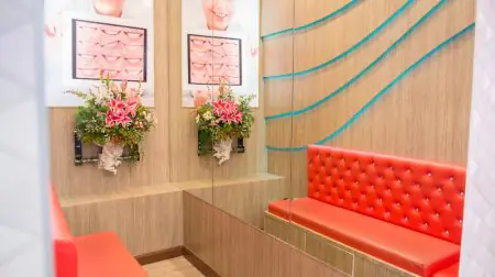 منطقة الانتظار في Siam Station Dental Clinic بمقاعد حمراء وملصقات طب الأسنان