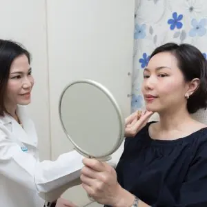 استشارة جلدية في ProDerma Clinic، مريضة تحمل مرآة