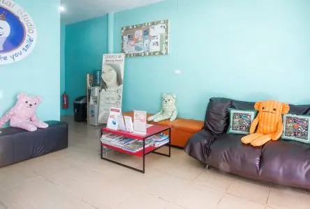 غرفة انتظار في Phuket Dental Studio مع أرائك وألعاب محشوة وكتيبات طب الأسنان