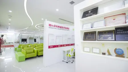 Sala de espera de Shanghai Y+bo Dental Clinic con sillones verdes y exhibición de premios