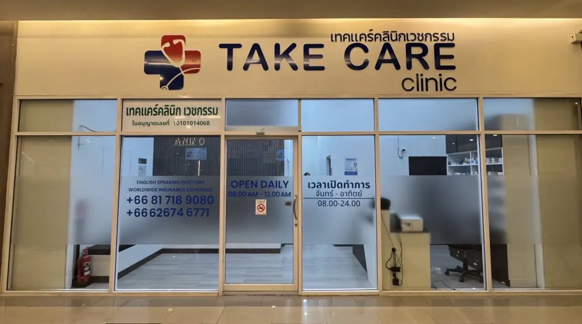 Fachada de la clínica Take Care Clinic Bangkok con entrada de vidrio y letrero
