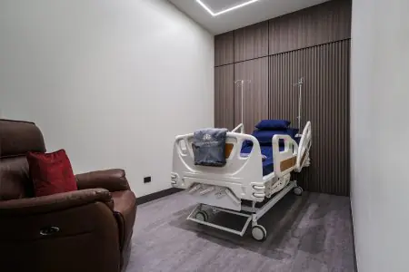Habitación de paciente en Miracle Regenerative Center con cama hospitalaria y sillón