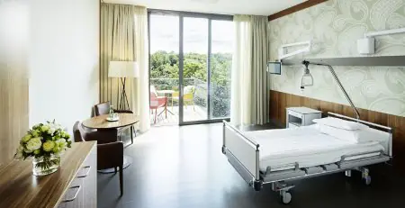 Habitación de paciente en la clínica Rudolfinerhaus Viena con balcón y mobiliario moderno