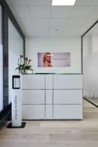 مكتب استقبال في عيادة REDEKER AESTHETICS مع محطة تعقيم وتصميم عصري