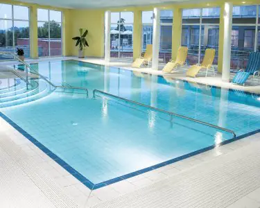 مسبح إعادة التأهيل في Private Clinic Lassnitzhöhe مع كراسي استلقاء ونوافذ كبيرة