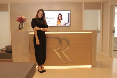 منطقة الاستقبال في عيادة Renata Ralha بديكور عصري ومكتب مضاء