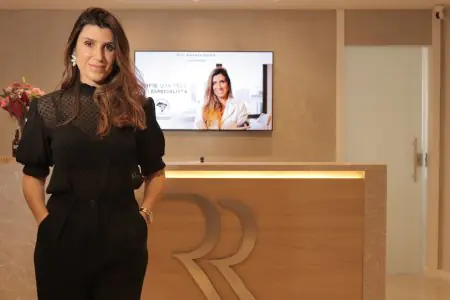 منطقة الاستقبال في عيادة Renata Ralha بديكور حديث وشعار على المكتب